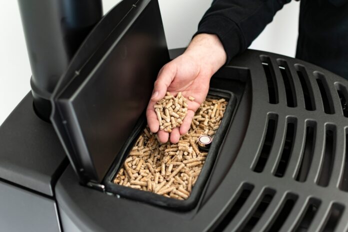 Pellet,Stove,,Man,Holding,Granules,In,His,Hand,Above,A