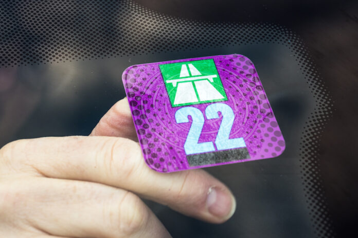 Berne, Bern, Switzerland - January 19, 2022: Replacing A a highway toll vignette for Switzerland for the new year. Has to be stuck on the front window of the car. Pricing imposed on vehicles.