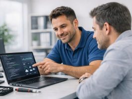 Assistenza computer Milano: tecnico informatico che assiste un cliente mostrando diagnostiche su laptop in ufficio moderno e luminoso